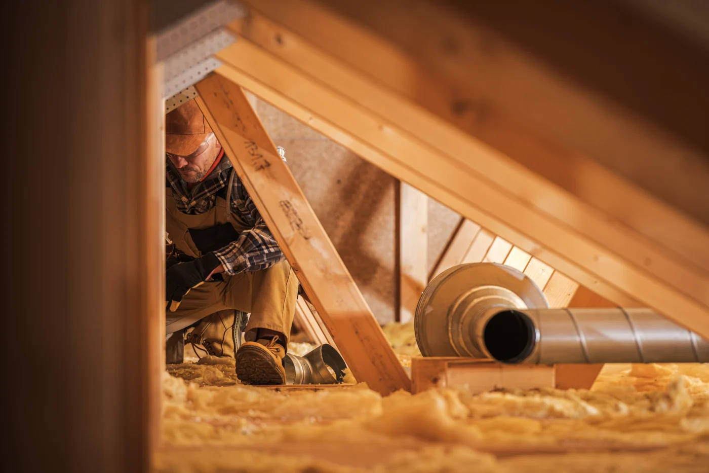 Worker installing insulation in attic of Memorial property