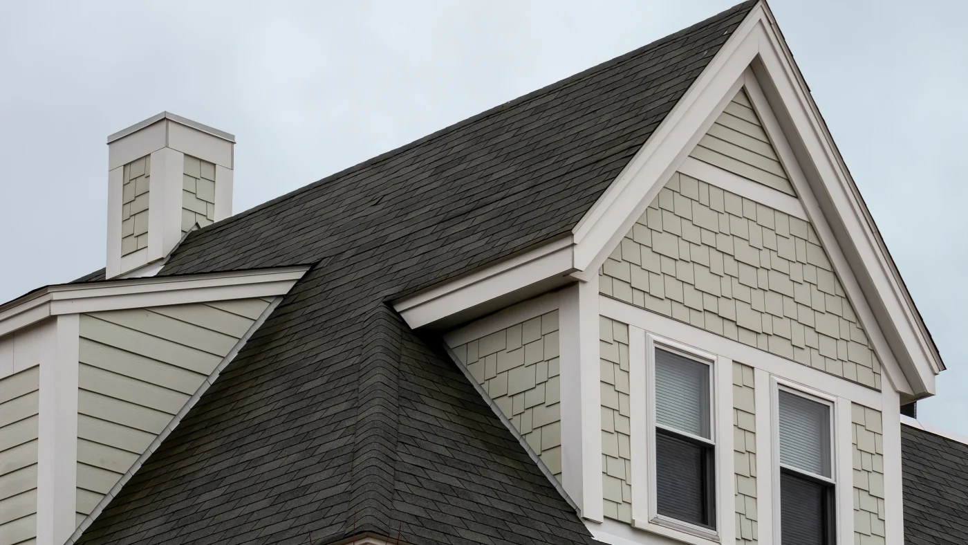 Close-up of a shingle roof on a home with tan siding