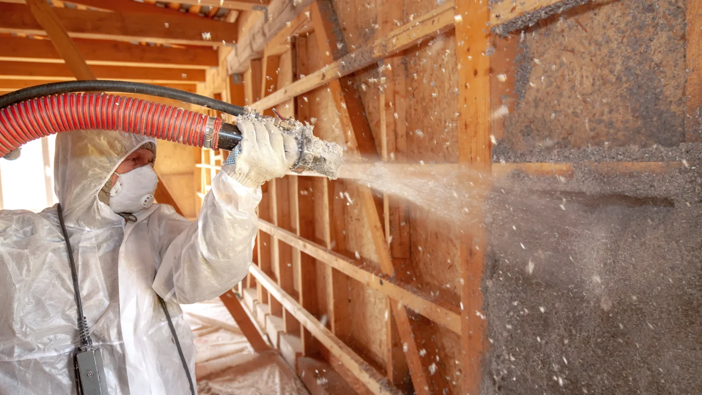 A contractor installs blown-in insulation