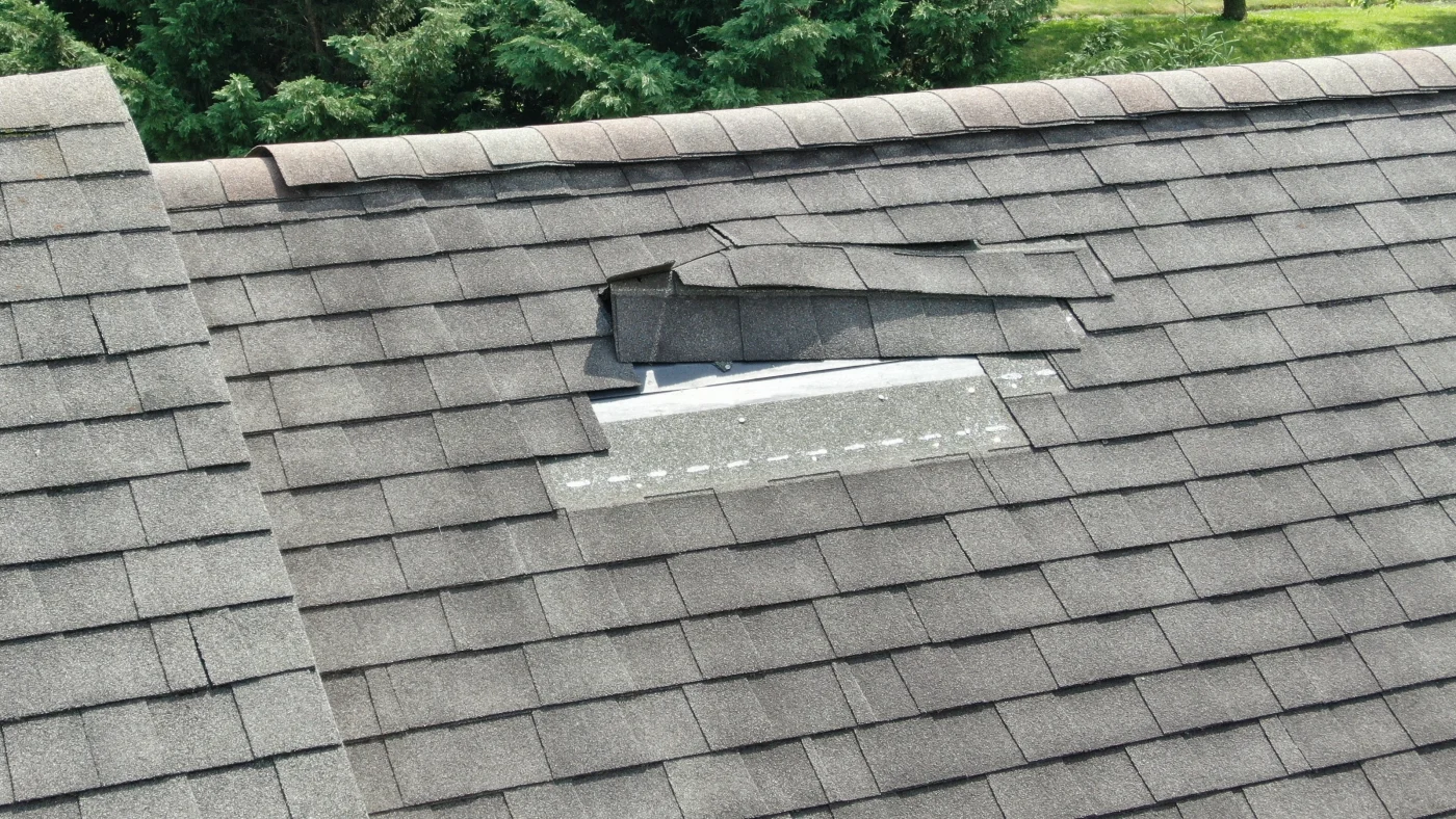 A gray shingle roof with lifted shingles