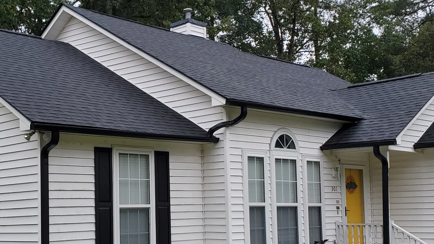 Black seamless gutters on a home with white siding