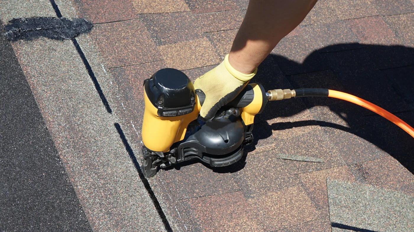 A roofing contractor completes repairs on a shingle roof