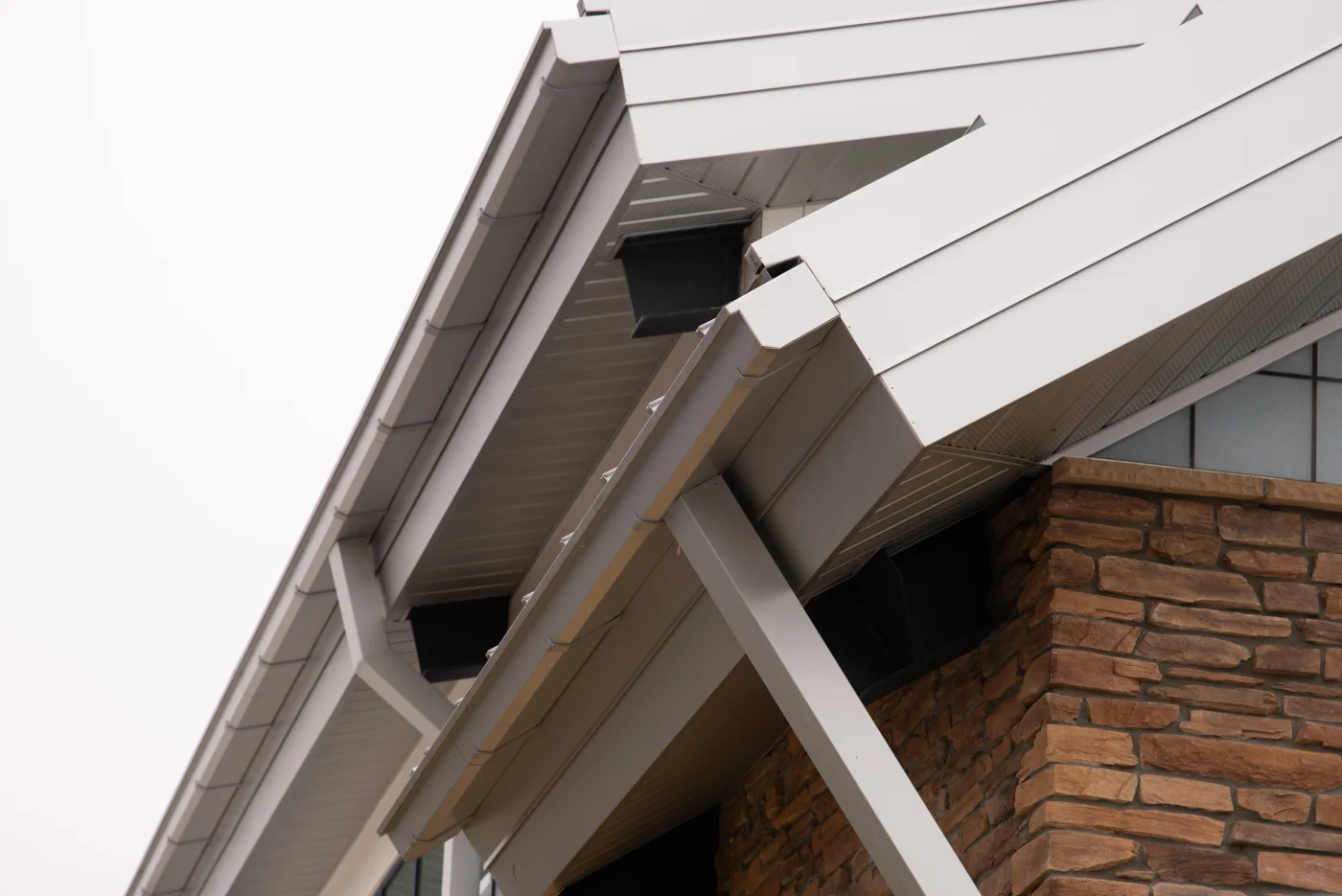 Close up view of gutters on the awning of a brick home with white fascia