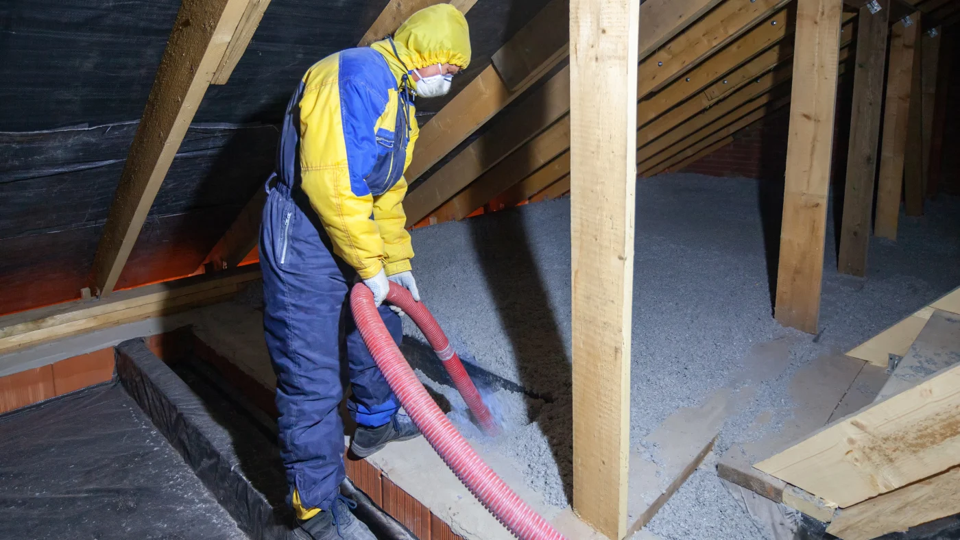 A contractor installs blown-in insulation