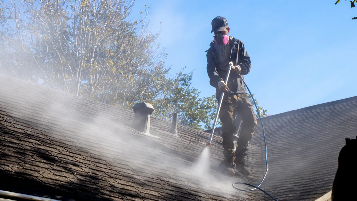 Proper roofer applying GoNano treatment to residential roof in greater houston