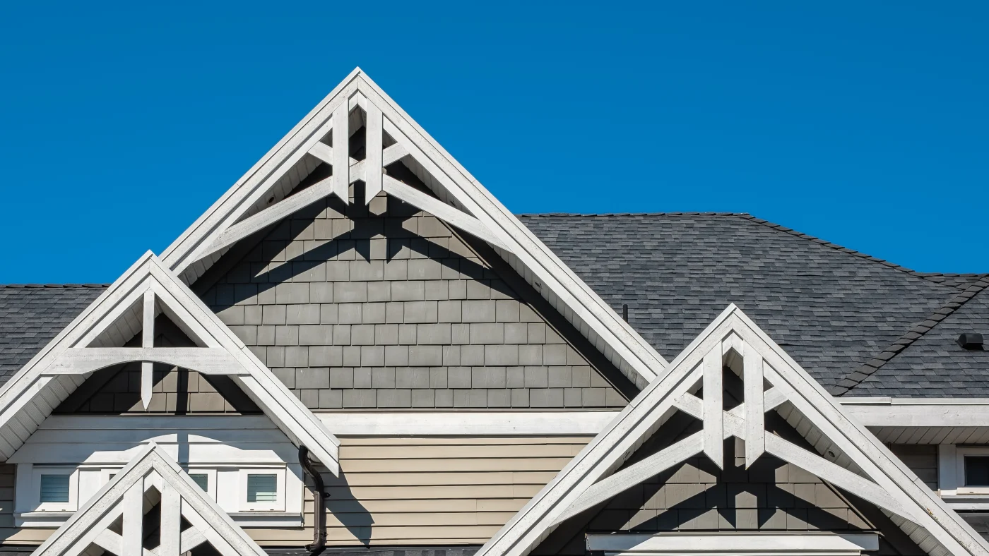 Close-up of the second story of a home with gray siding, white trim, and a gray shingle roof
