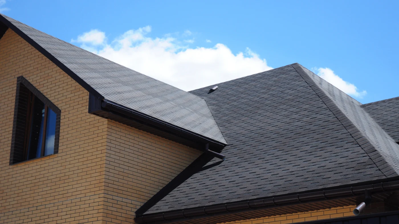 A brick home with an asphalt shingle roof