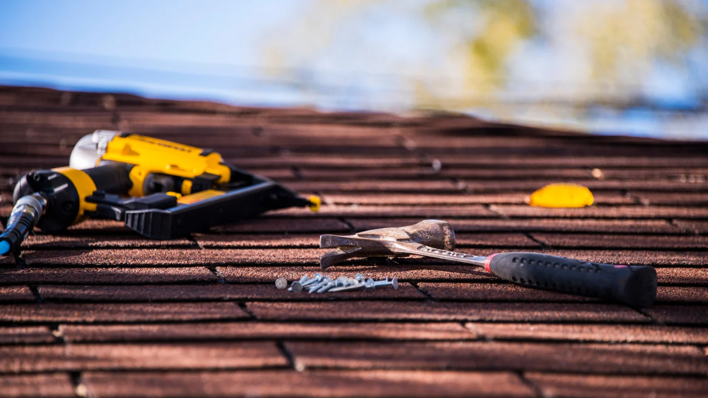 Roofers' tools rest on asphalt shingles